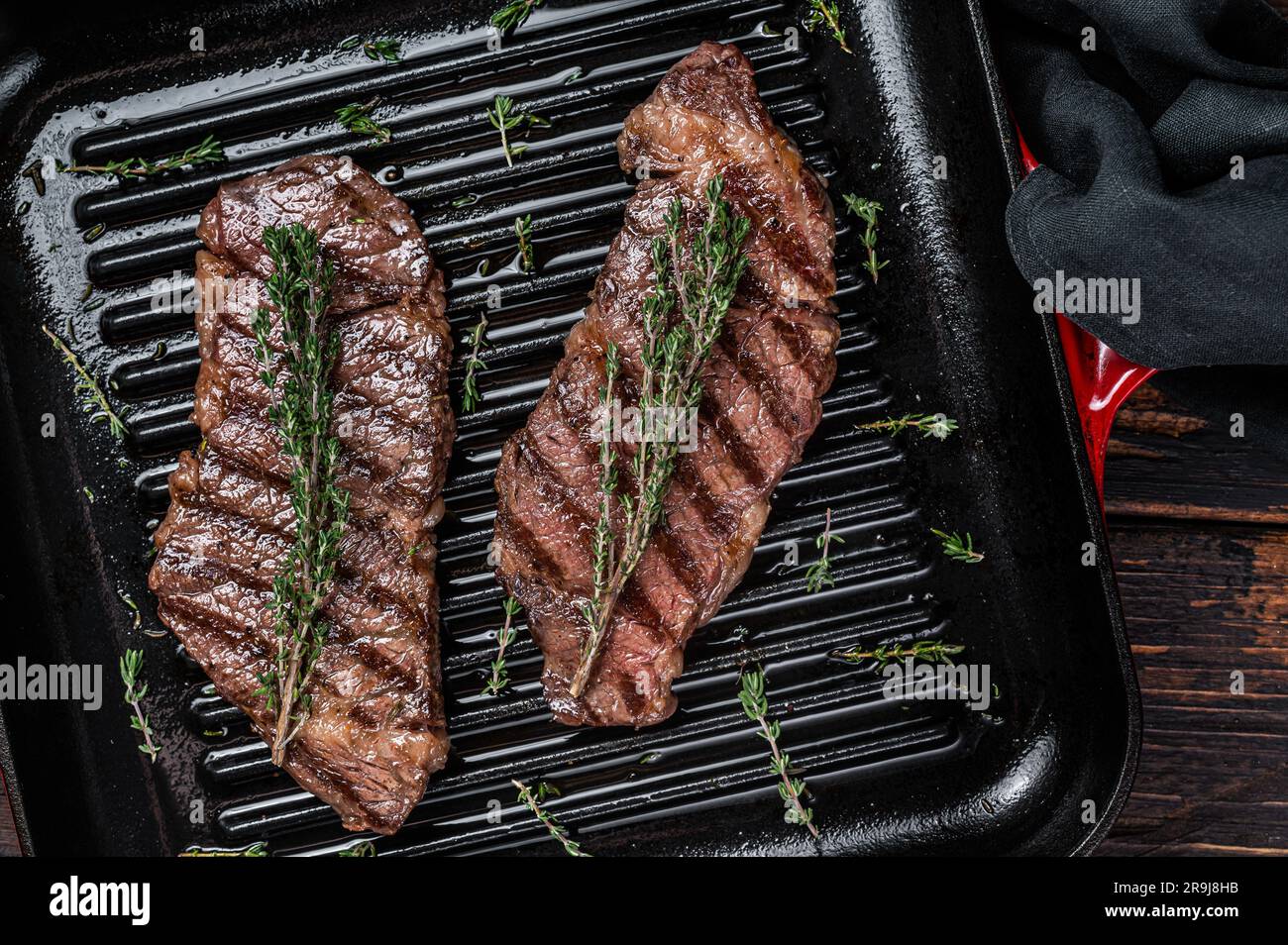 Steak de viande de bœuf de denver frits au thym dans une poêle à frire. Arrière-plan en bois. Vue de dessus. Banque D'Images