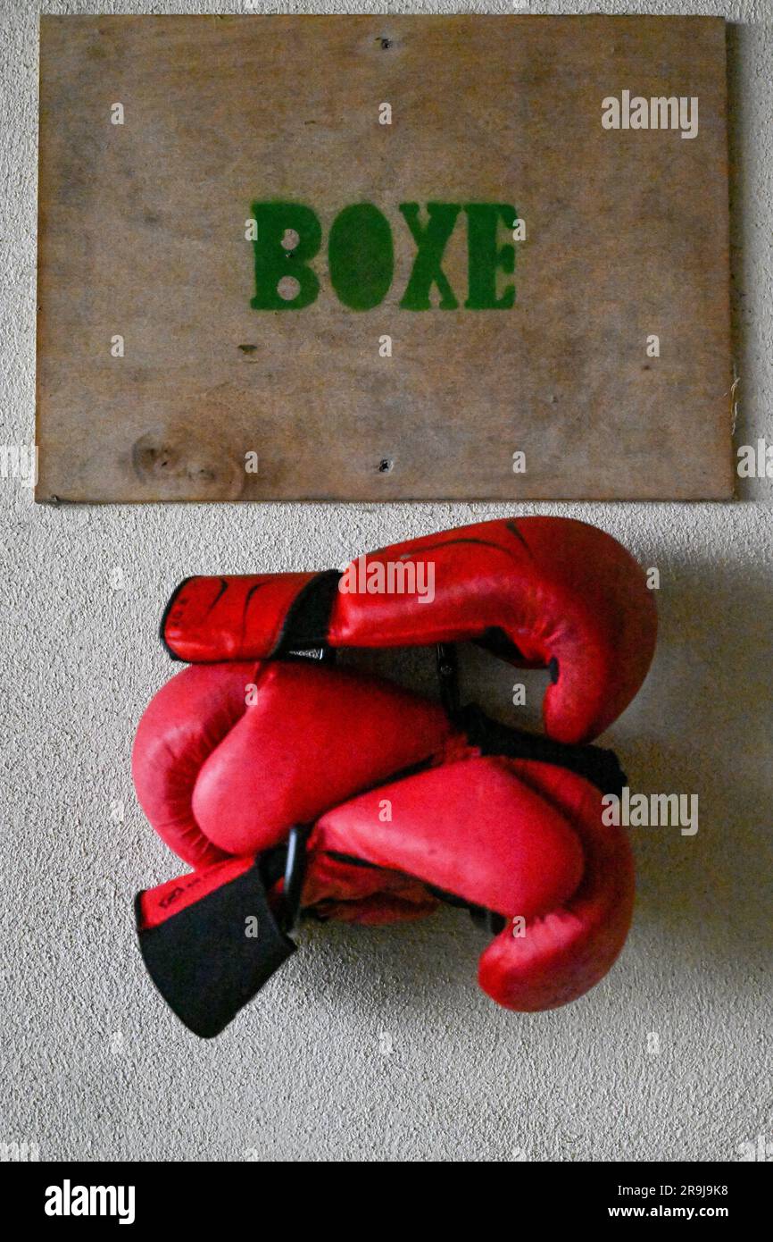 Deux gants de boxe rouges sont suspendus sur une plaque de bois avec une boîte et une inscription Banque D'Images