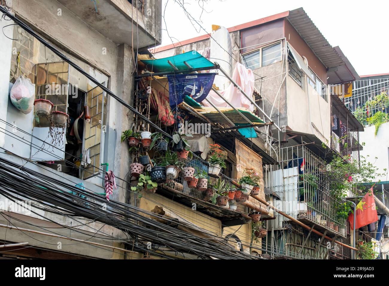 Hanoï, Vietnam-avril 2023; vue à angle bas de la façade de maisons typiques avec balcons avec câbles électriques, lignes téléphoniques accrochées dans le désordre Banque D'Images