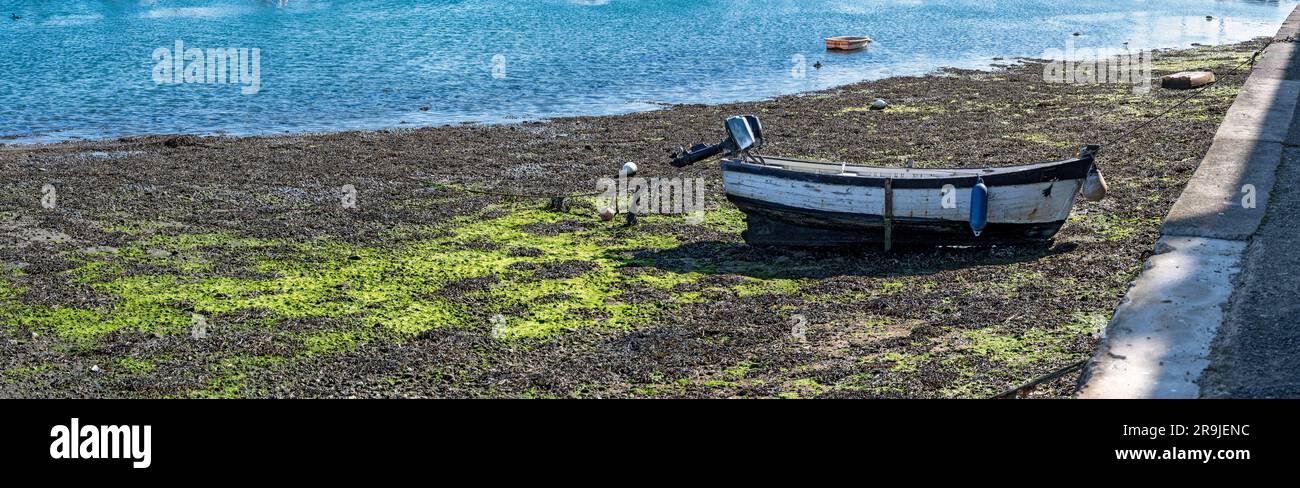 Le vieux bateau avec des moteurs hors-bord tombe sec à marée basse dans le port de Concarneau en Bretagne, France Banque D'Images