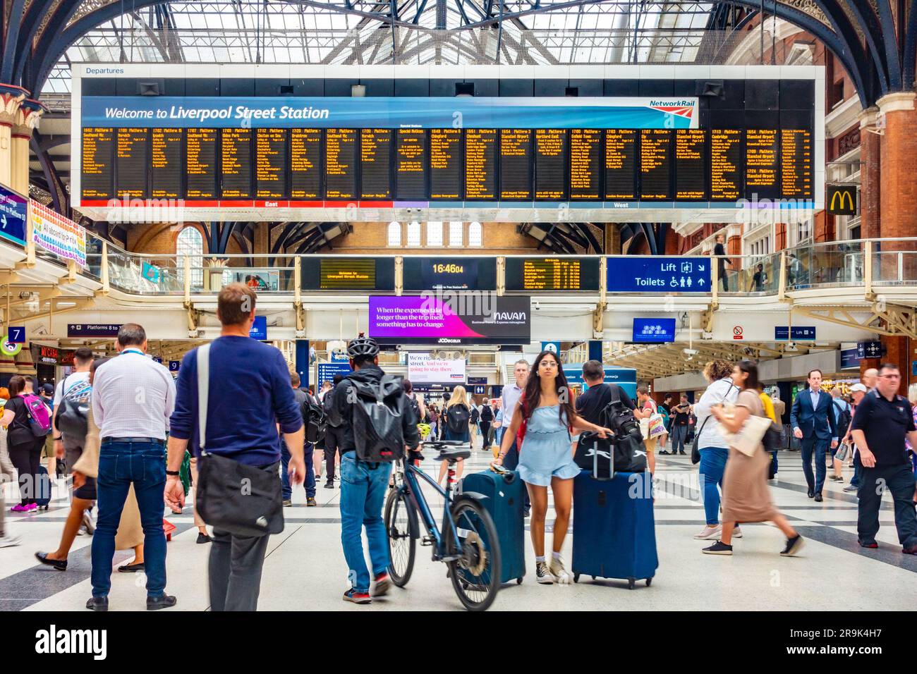 Grand écran de départ électronique à la gare de Liverpool Street à Londres, Royaume-Uni. La gare est occupée par les passagers. Banque D'Images