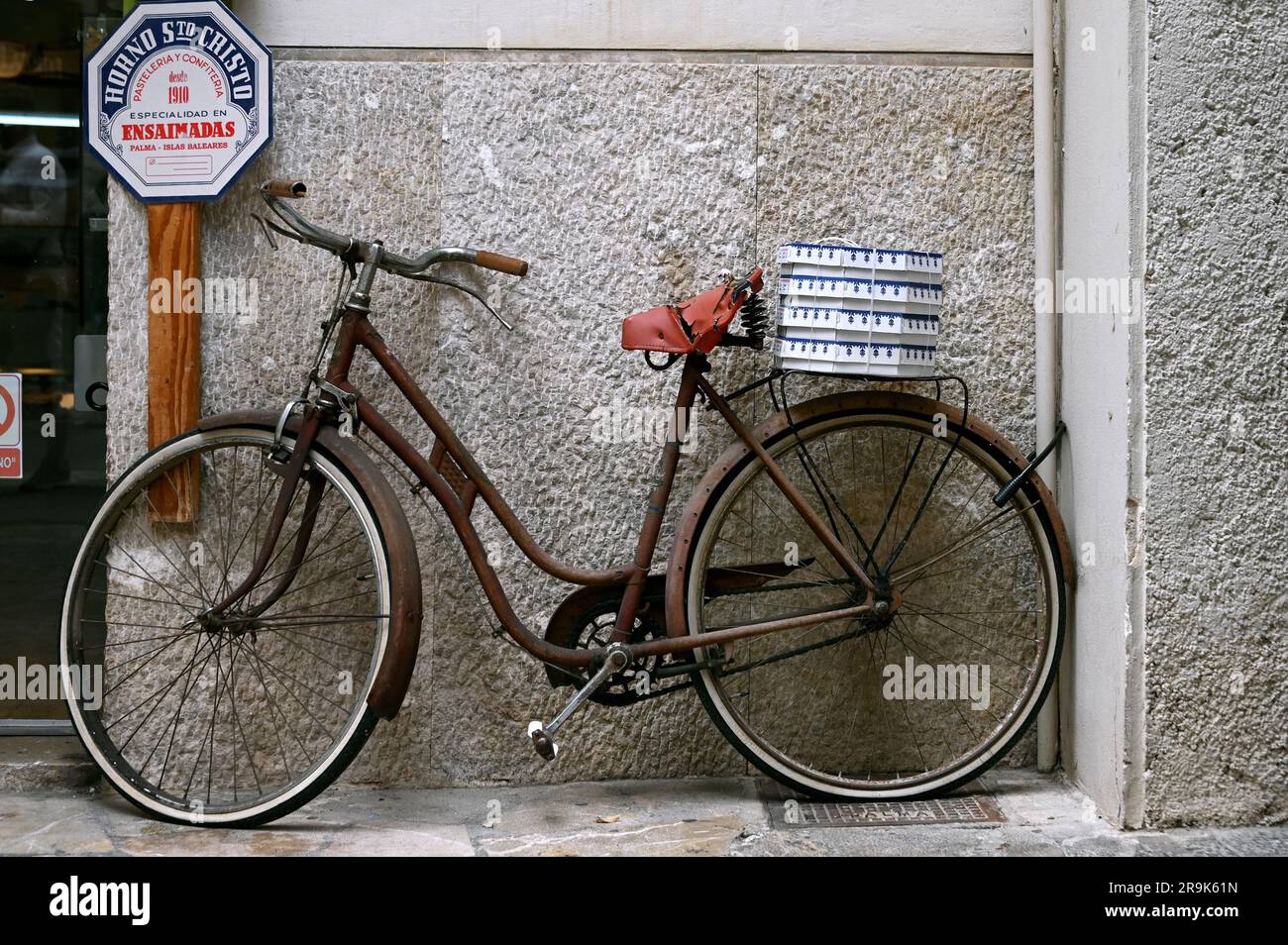 Vieux vélo avec forfaits ensaimada sur le rack en face d'une boulangerie, Palma de Majorque, Espagne Banque D'Images