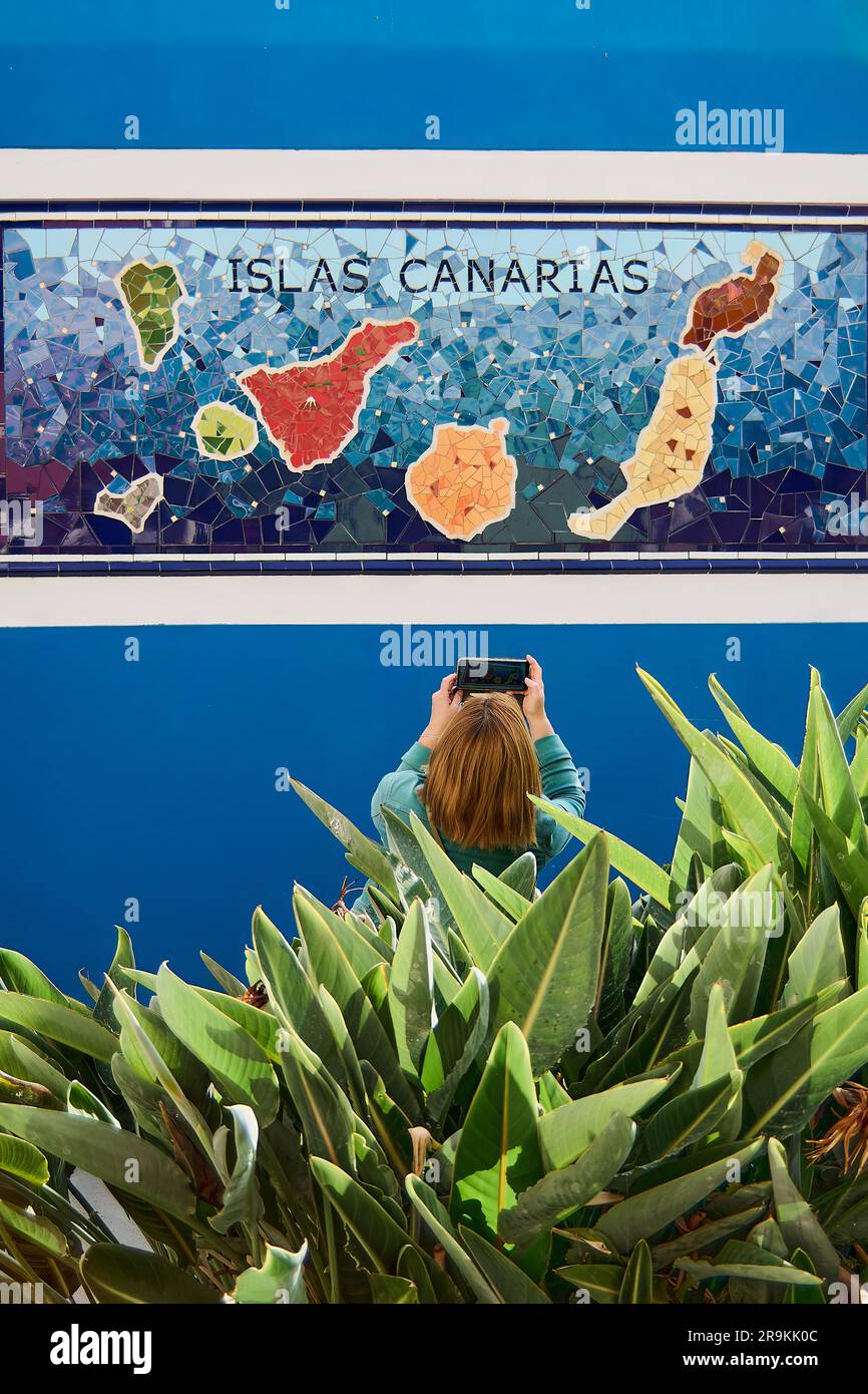 Ténérife, Espagne - 27 juin 2023: Femme méconnaissable prenant une photo avec son téléphone portable d'une carte des îles Canaries. Banque D'Images