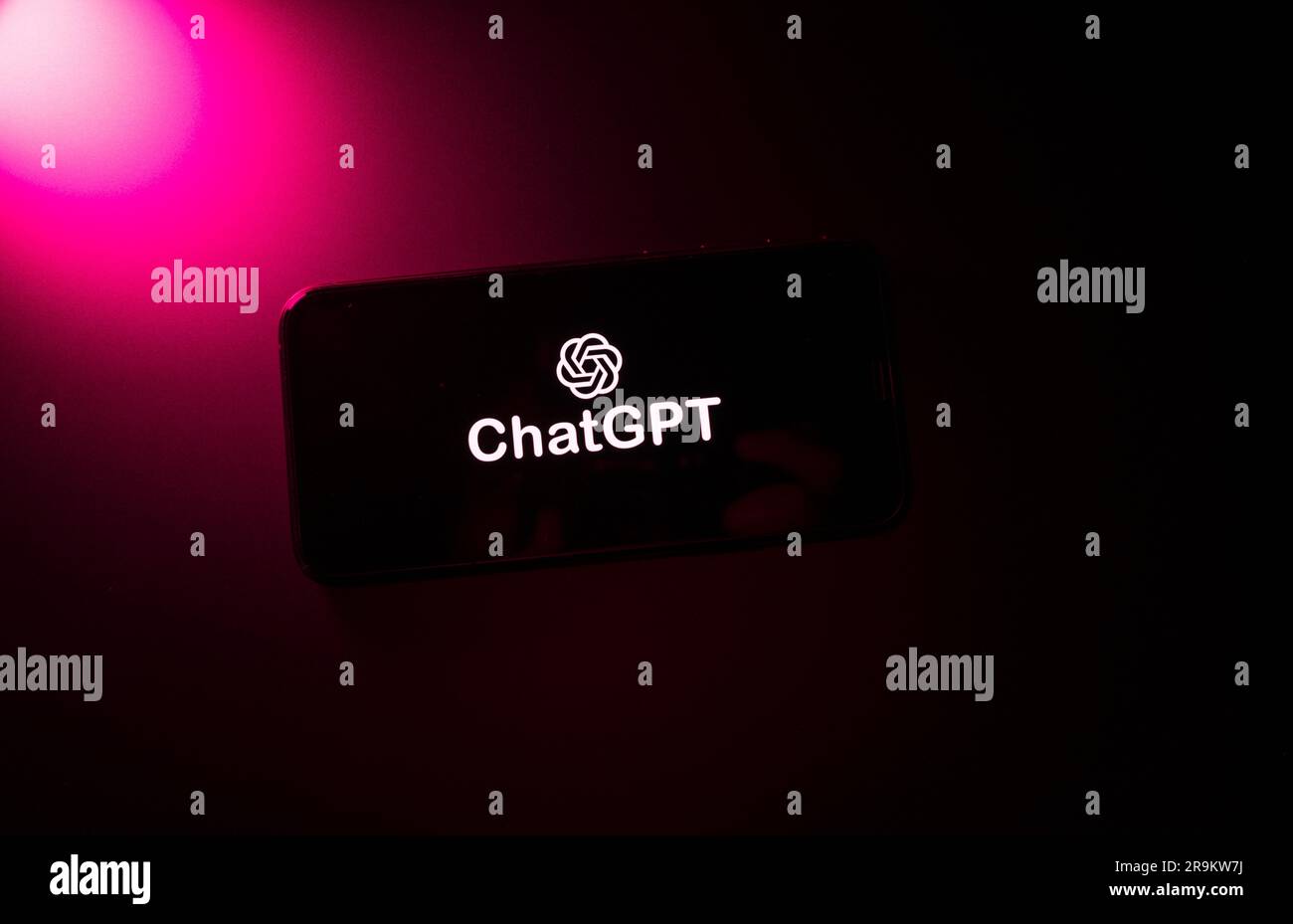 Açores, Portugal - 21.01.2023 : smartphone avec ChatGPT mot sur écran sombre, avec effet de couleur magenta lumineux sur un fond sombre. Banque D'Images