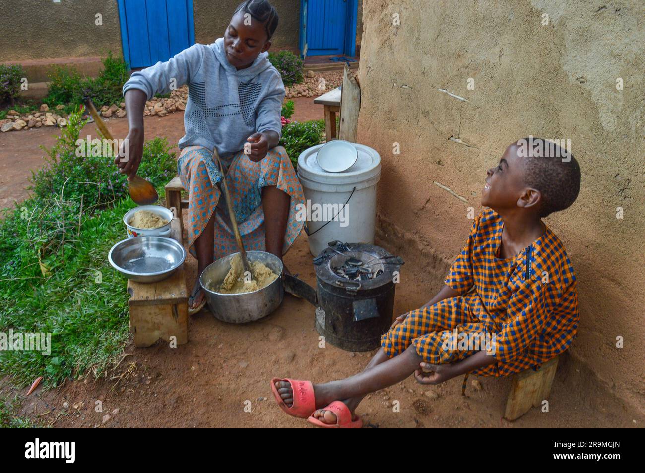 Merci Kahindo Wasakundi fait une pâte à partir de manioc et de farine de maïs tandis que son frère Asher Saruti, 6 ans, regarde sur 17 mai 2023 à Kirumba, Nord-Kivu, République démocratique du Congo. La pâte est ajoutée à une sauce faite de haricots et de sombe, un ragoût de feuilles de manioc. (Merveille Kavira Luneghe/Global Press Journal) Banque D'Images