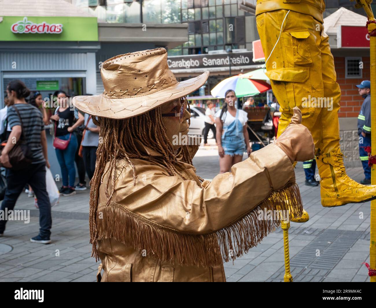 Medellin, Antioquia, Colombie -21 novembre 2022: Représentation d'artistes de rue, une femme couverte d'or, portant un chapeau et des lunettes près de la Sta du métro Banque D'Images
