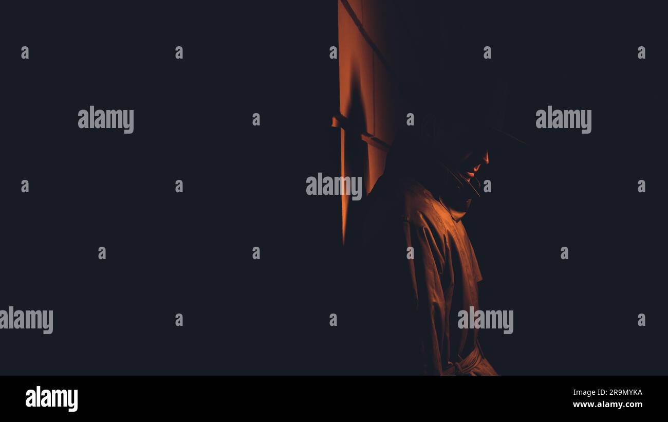 un détective mafieux masculin dans un chapeau et un imperméable la nuit dans le style de film noir Banque D'Images