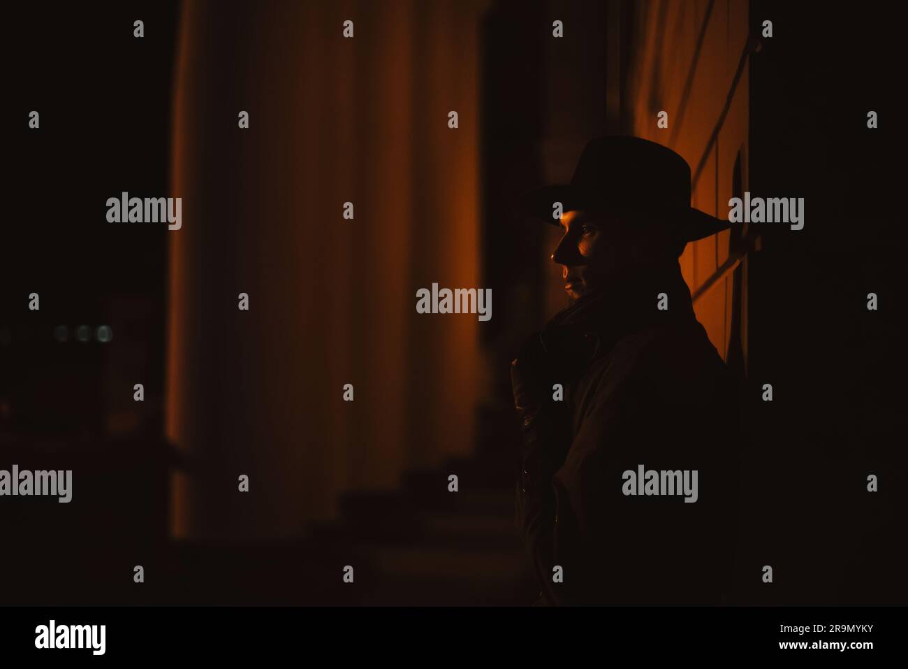 un détective mafieux masculin dans un chapeau et un imperméable la nuit dans le style de film noir Banque D'Images