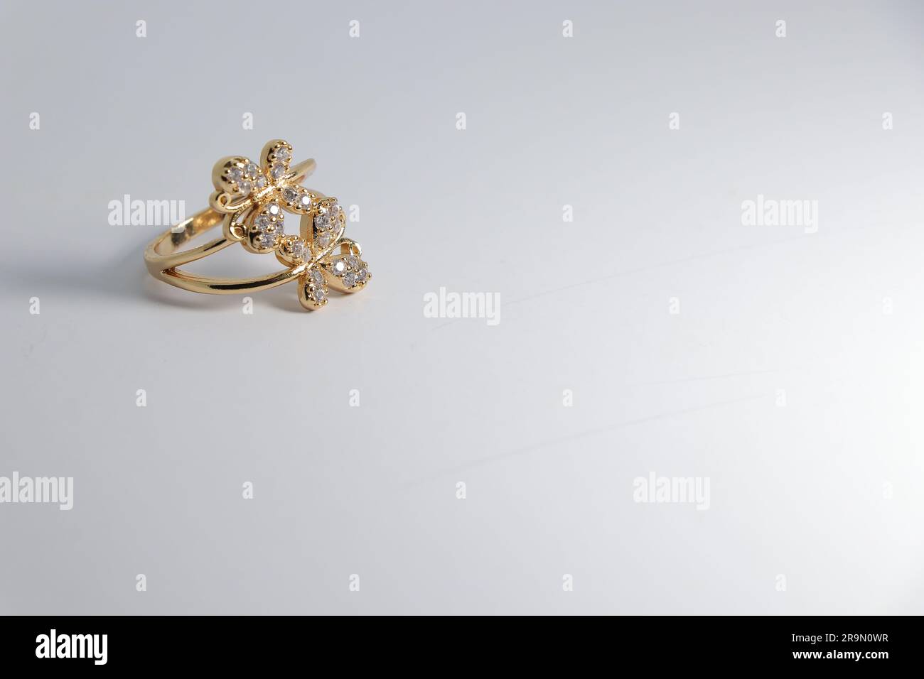 Brilliance élégante : bague d'or artificielle avec pierre blanche sur toile blanche - parfait pour la vente en ligne! Banque D'Images