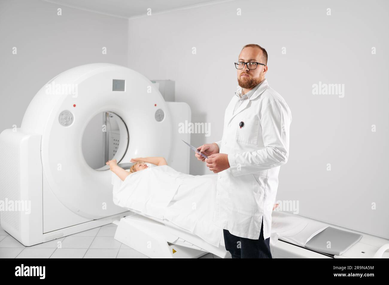 Scanner médical de tomodensitométrie ou IRM. Portrait du médecin tenant et examinant les résultats de l'IRM. Femme patiente couchette. Concept de médecine, de soins de santé et de diagnostic moderne. Banque D'Images