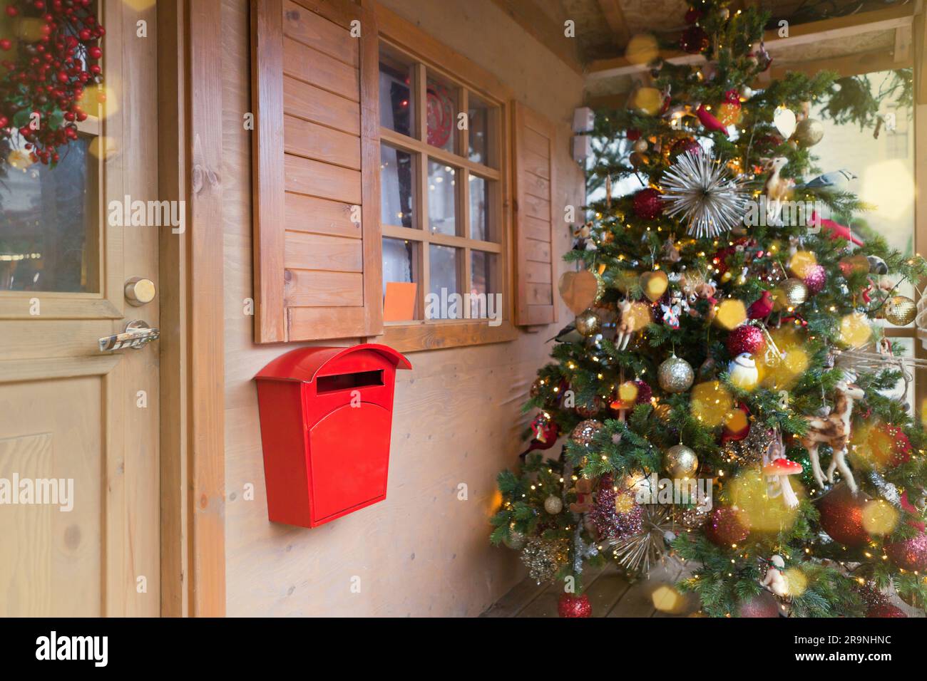 Boîte aux lettres rouge du Père Noël sur une maison en bois près de l'arbre de noël. Lettres au Père Noël Banque D'Images