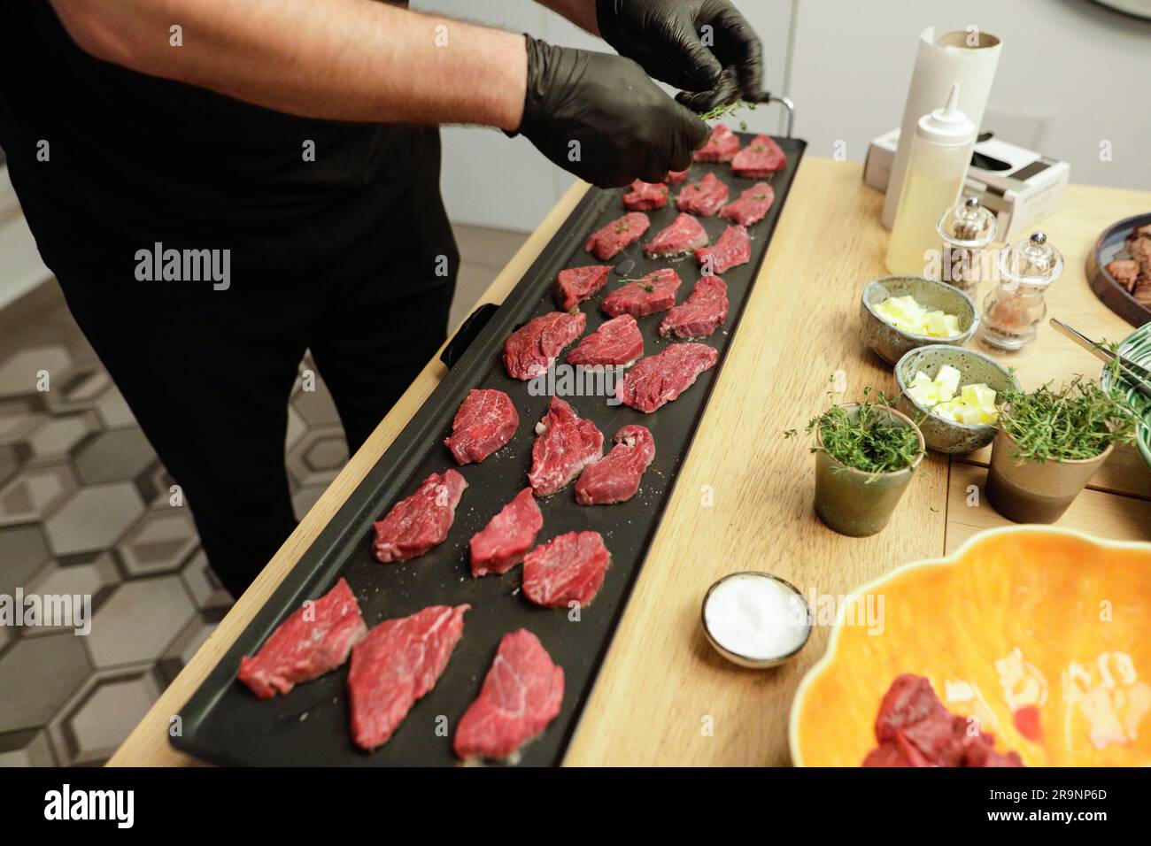 Profondeur de champ peu profonde (mise au point sélective) détails avec steak de boeuf cuit par un chef sur une cuisinière avec du beurre, du sel et du romarin. Banque D'Images