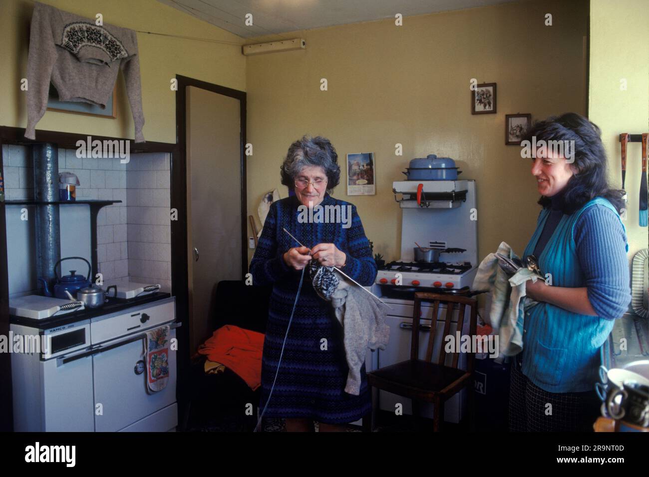 Femmes Crofters Écosse. Une famille crofting, mère et fille dans leur cuisine. La femme plus âgée tricote un pull Fair Isle, l’un d’entre eux a été lavé et est accroché pour sécher au-dessus du poêle, avant d’être vendu dans un magasin local. Shetlands Mainland, îles Shetland, Écosse, vers 1979. ROYAUME-UNI 1970S HOMER SYKES Banque D'Images