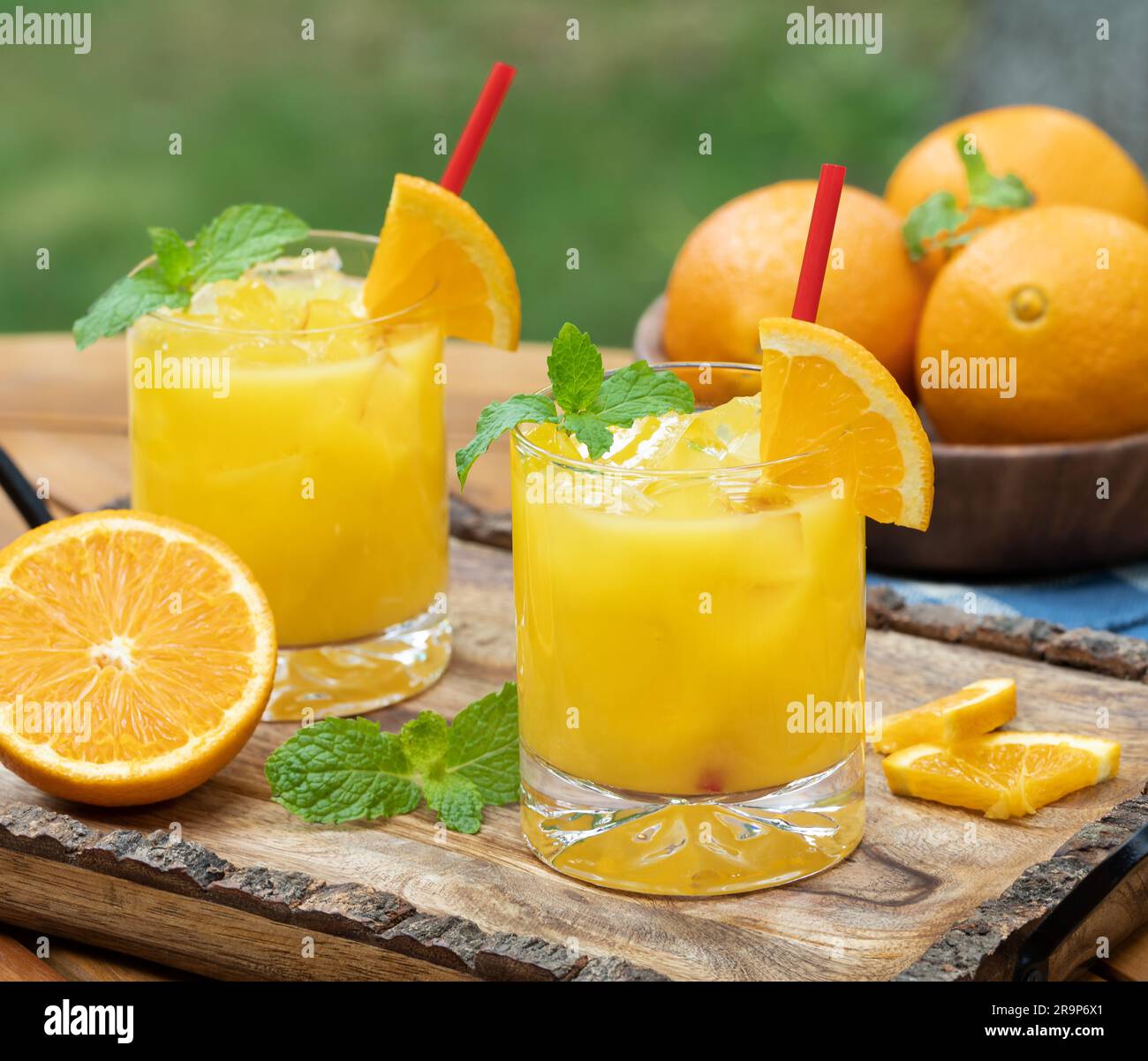 Cocktail de jus d'orange avec des tranches de menthe et d'orange à l'extérieur sur un plateau en bois Banque D'Images