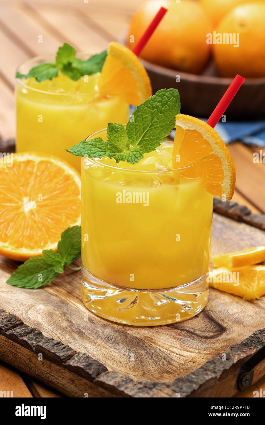 Cocktail de jus d'orange avec des tranches de menthe et d'orange à l'extérieur sur un plateau en bois Banque D'Images