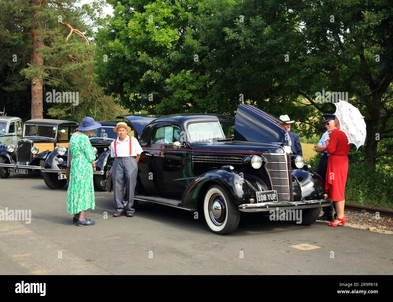 Une voiture Chevrolet de 1938 avec des personnes vêtues en costume d'époque à la gare d'Arley, sur le chemin de fer de la vallée de Severn. Banque D'Images