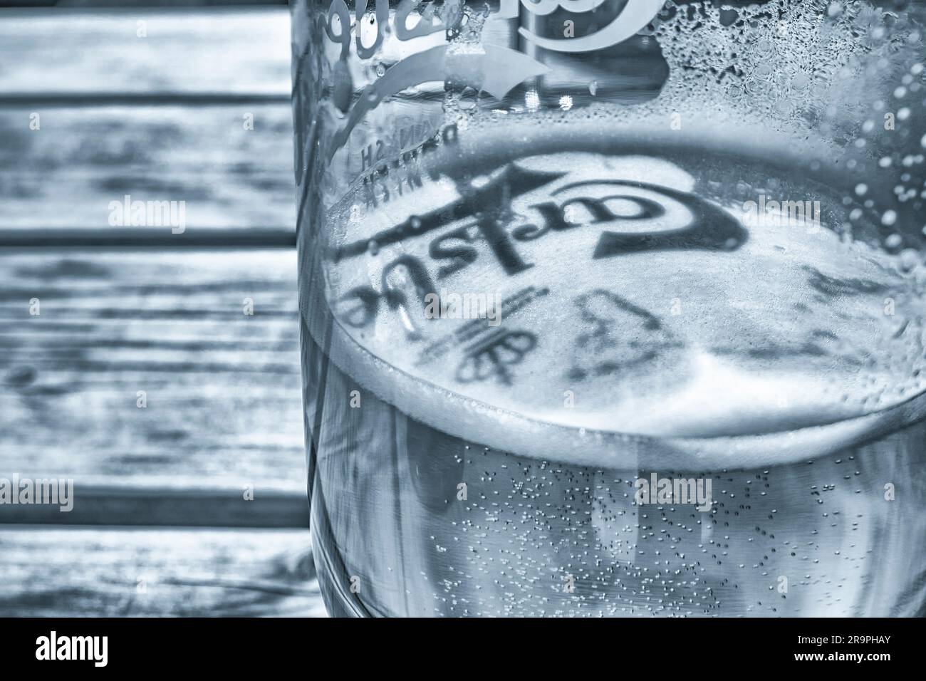 Monochrome teinté froid de Moody de verre à bière Carlsberg sur la table de jardin de bière dans la lumière du soleil de l'après-midi. Voir Remarques sur le point focal. Froid de glace dans Alex Pun Banque D'Images