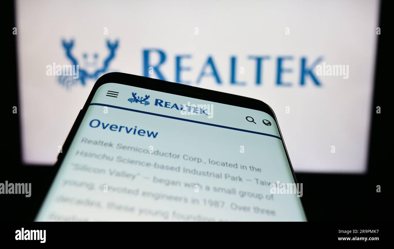 Smartphone avec le site Web de la société taïwanaise Realtek Semiconductor Corp. à l'écran devant le logo de l'entreprise. Faites la mise au point dans le coin supérieur gauche de l'écran du téléphone. Banque D'Images