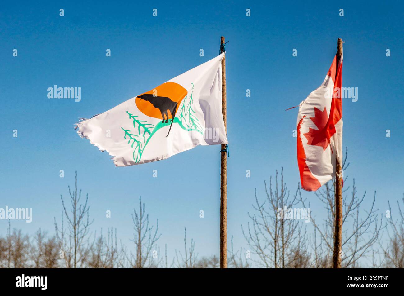 Un drapeau de la première nation d'Attawapiskat effiloché s'envole aux côtés d'un drapeau canadien en lambeaux dans la communauté autochtone isolée d'Attawapiskat, dans le nord de l'Ontario Banque D'Images