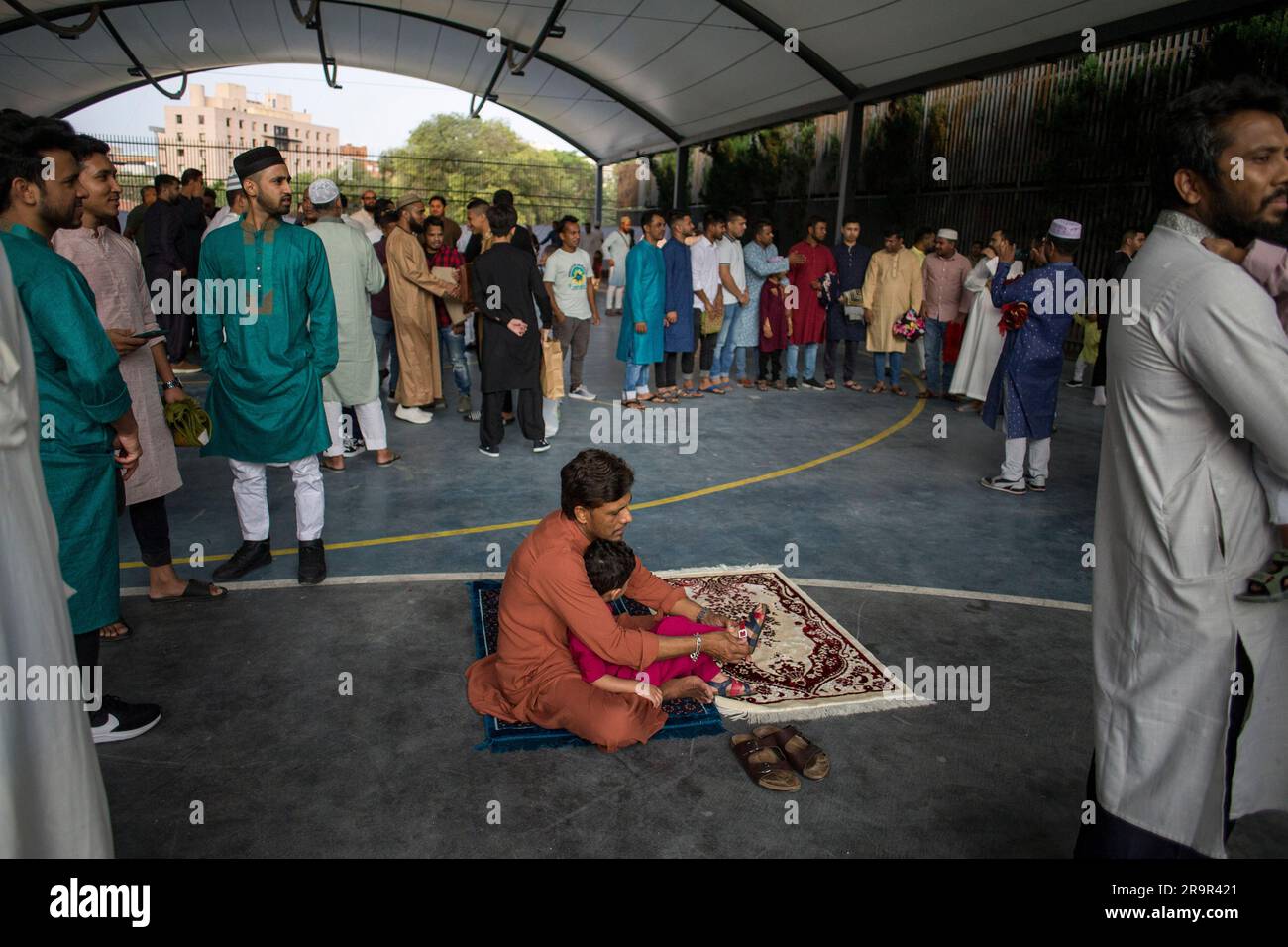 Madrid, Espagne. 28th juin 2023. Un père aide à mettre sur les sandales de son fils après avoir terminé la première prière pendant la célébration de la Fête de l'Agneau, 'Eid al Adha'. La communauté musulmane de Madrid, réunie dans le quartier des Lavapies pour prier lors de la célébration de la Fête de l'Agneau, 'Eid al Adha', cette fête symbolise la dévotion et la gratitude envers Dieu, en rappelant qu'Abraham a accepté de tuer son propre fils comme un signe de son amour pour lui. Crédit : SOPA Images Limited/Alamy Live News Banque D'Images