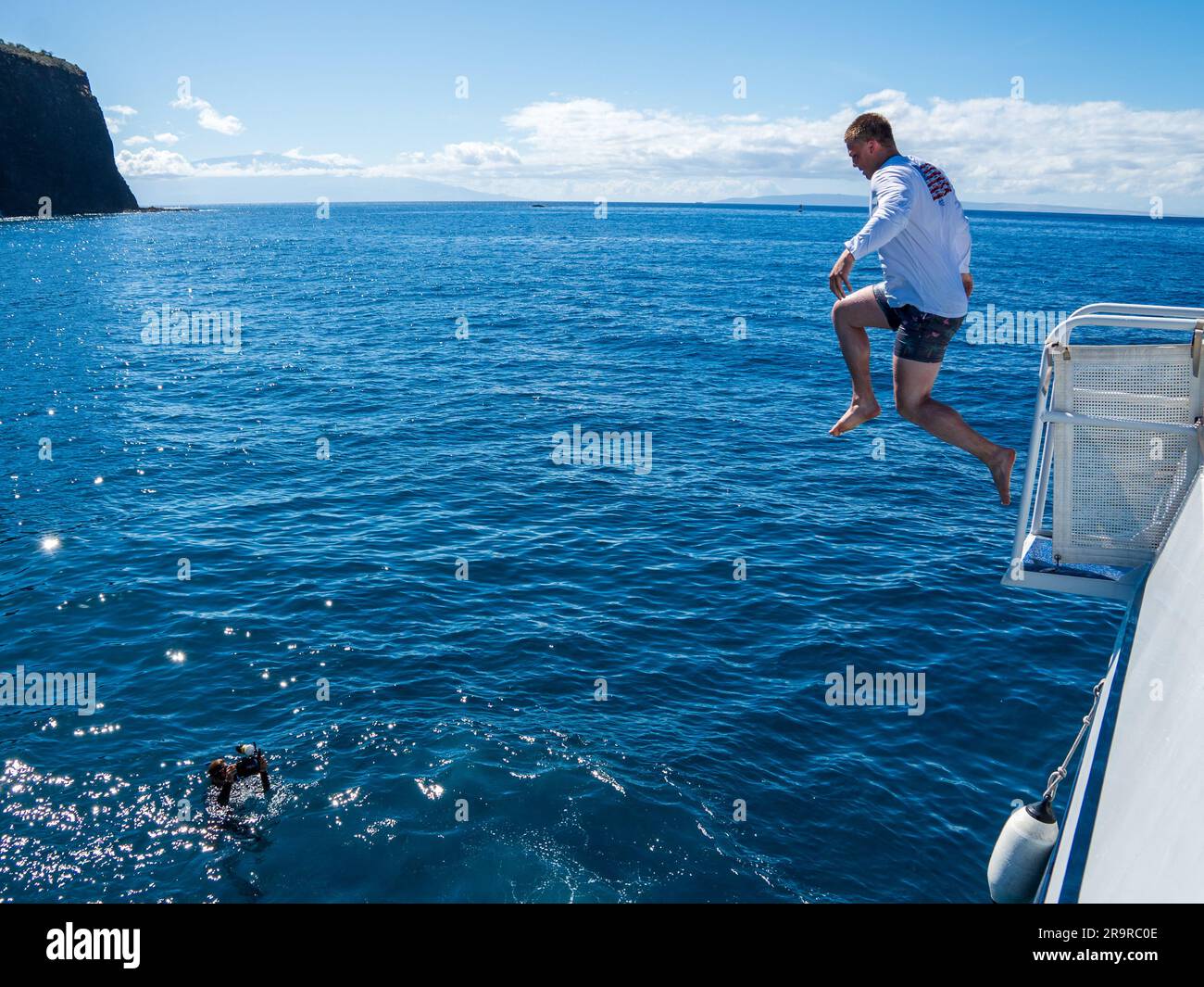 Les gens sautent joyeusement d'un bateau dans les eaux claires et chaudes de l'océan Pacifique au large des rives de Lanai, Hawaï Banque D'Images