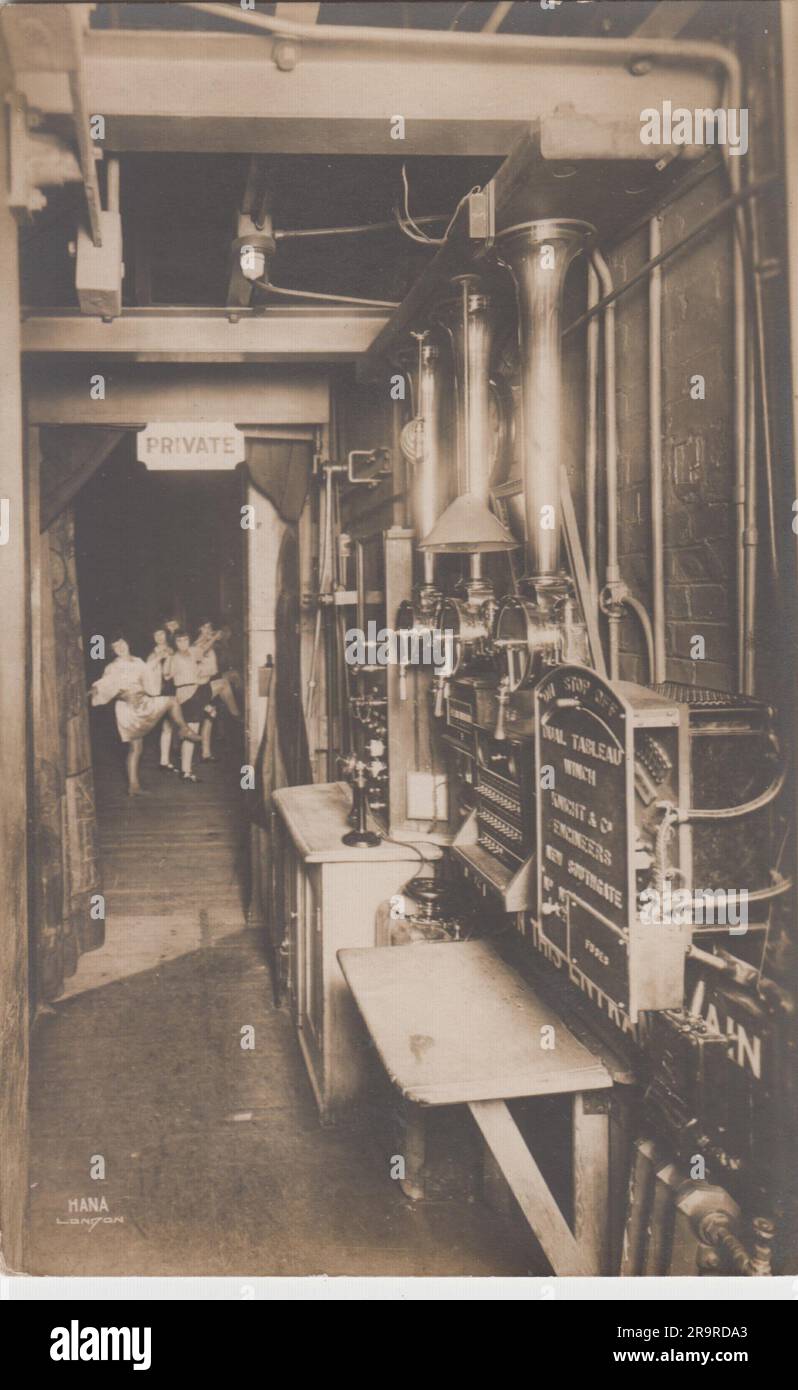 Coulisses du théâtre édouardien : photographie du début du 20th siècle prise des ailes d'un théâtre londonien. Une ligne de filles de danse de coup de pied élevé peut être vu par la porte à la scène, regardant vers la caméra. Les machines de scène peuvent être vues sur le côté droit, y compris les treuils pour lever des rideaux et des paysages Banque D'Images