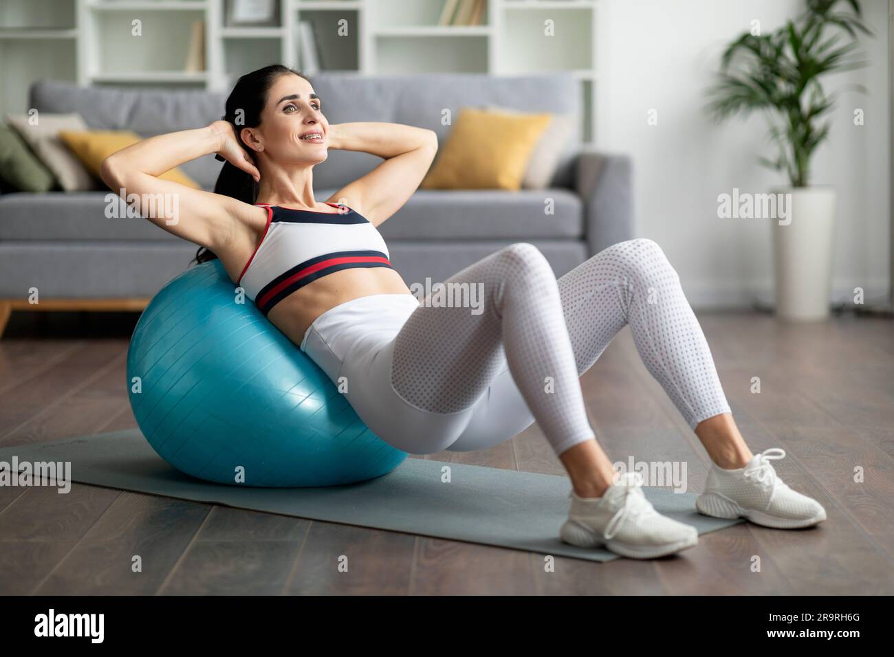 Jeune femme athlétique faisant des exercices avec le ballon de mise en forme à la maison Banque D'Images