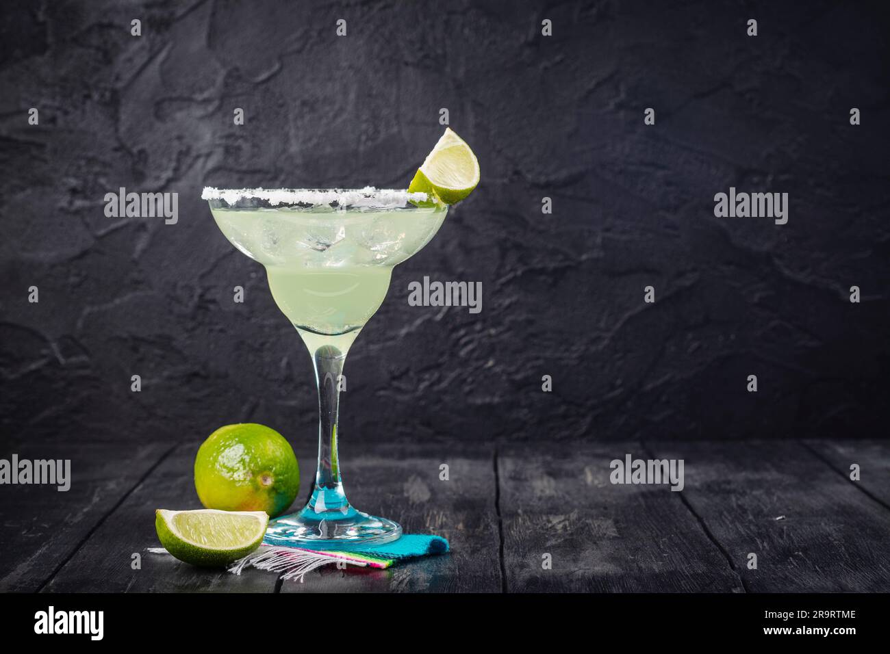 Cocktail de Margarita avec rondelles et limes entières sur une table de bar en bois. Ambiance de fête mexicaine Banque D'Images