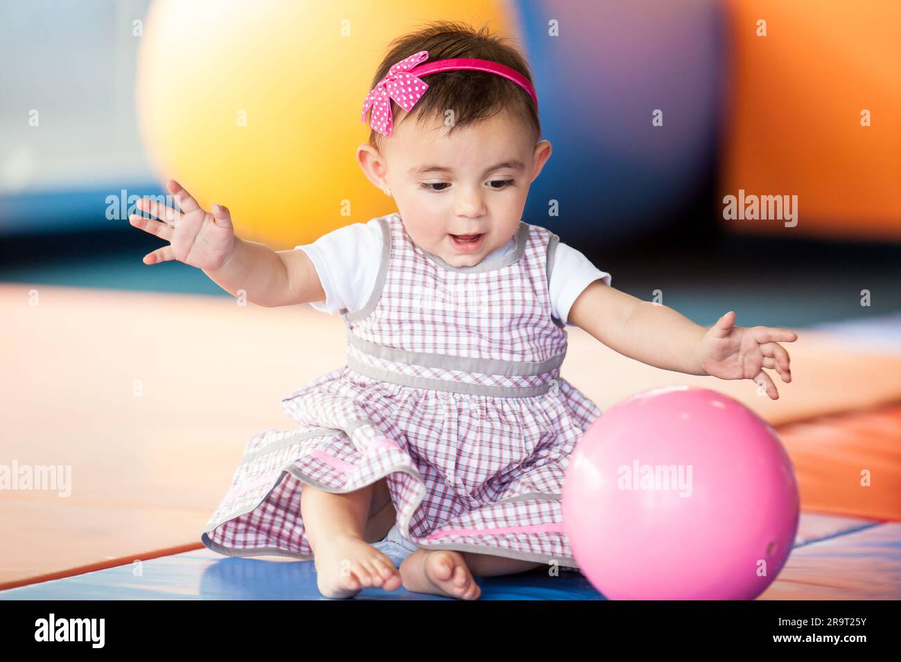 Belle fille de dix mois de bébé jouant avec une balle colorée. Concept de stimulation précoce pour les tout-petits. Banque D'Images