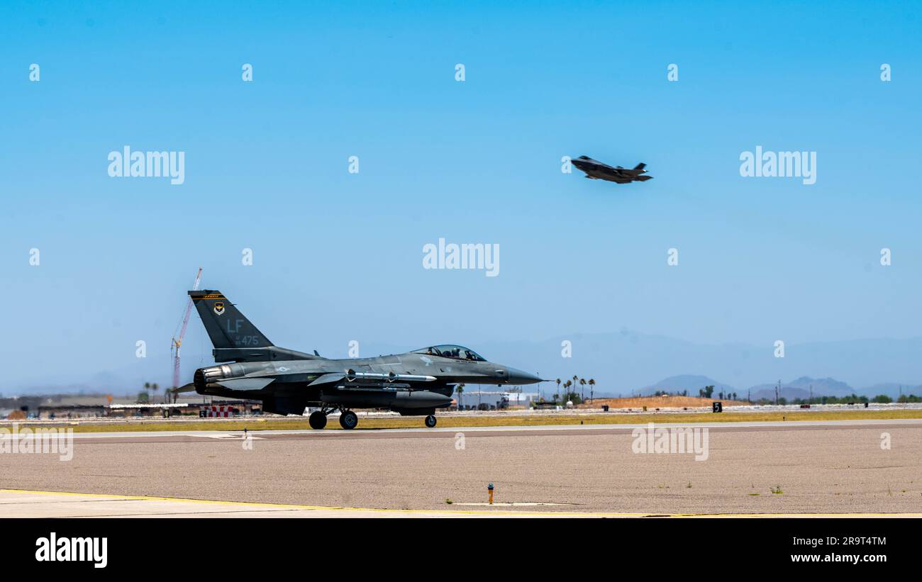 Un faucon de combat F-16 affecté à l'aile 56th Fighter, des taxis sur la ligne de vol tandis qu'un F-35 Lightning II prend le dessus de la base aérienne de Luke, Arizona 23 juin 2023. Luke est une base de formation de pilotes de chasse dédiée à la production des plus grands pilotes de chasse et des aviateurs prêts au combat du monde. (É.-U. Photo de la Force aérienne par Airman 1st classe Elias Carrero) Banque D'Images