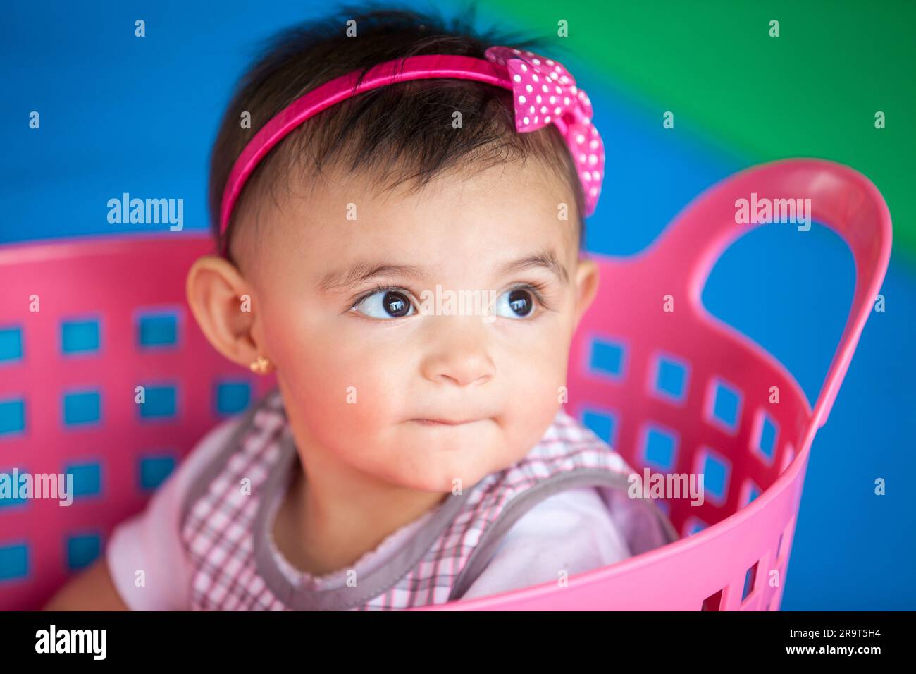 Belle fille de dix mois de bébé jouant dans un panier rose. Concept de stimulation précoce pour les tout-petits. Banque D'Images