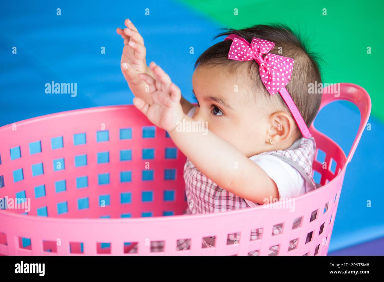 Belle fille de dix mois de bébé jouant dans un panier rose. Concept de stimulation précoce pour les tout-petits. Banque D'Images