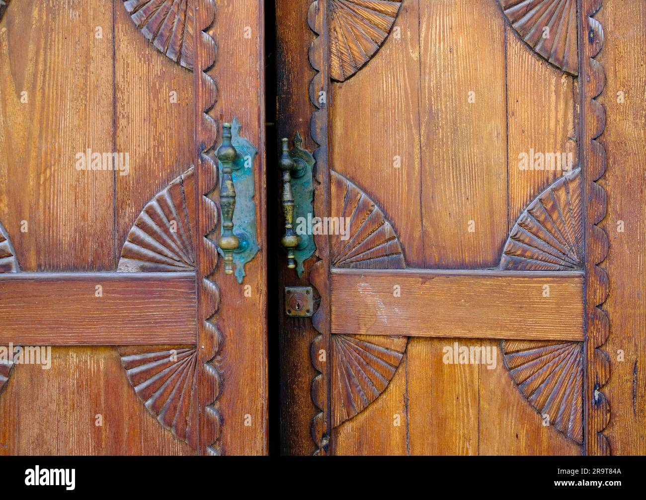 Porte à moitié ouverte entrouverte, porte en bois chaude décorative avec poignées en bronze. Banque D'Images