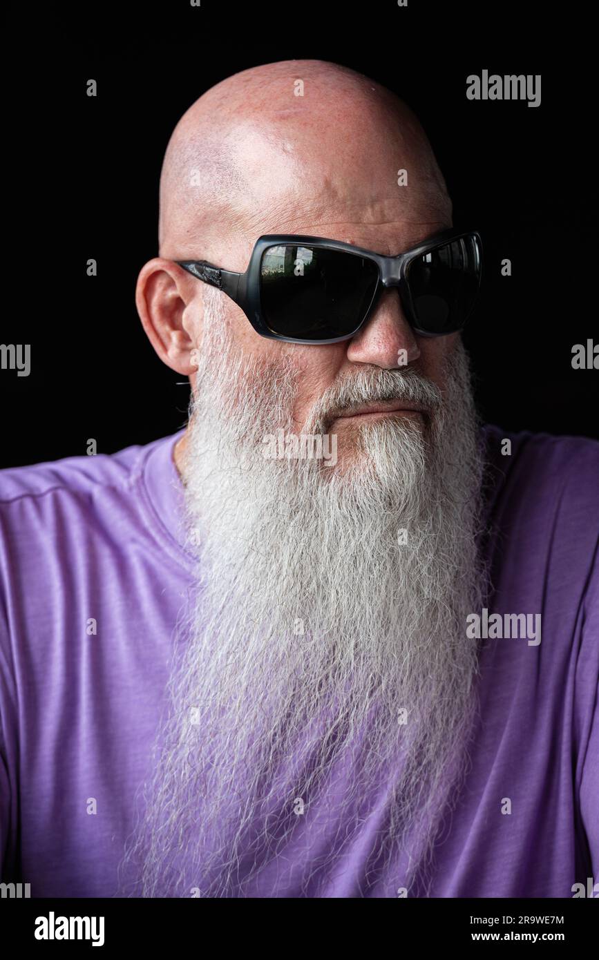 Portrait d'un homme avec une longue barbe grise portant un t-shirt violet et des lunettes de soleil gros plan Banque D'Images