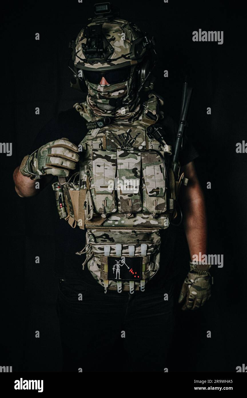 Un soldat déterminé en uniforme de camouflage complet et casque tactique se tient prêt avec une arme, prêt à relever n'importe quel défi Banque D'Images