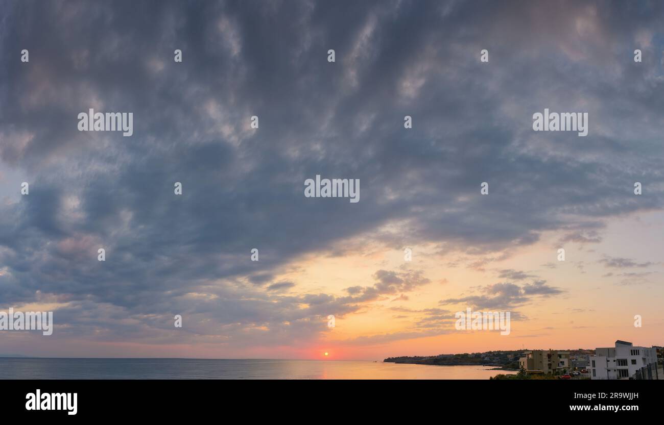 aube spectaculaire en mer. nuages gris sur le ciel avec soleil rouge au-dessus de l'horizon. vacances d'été météo pluvieuse Banque D'Images