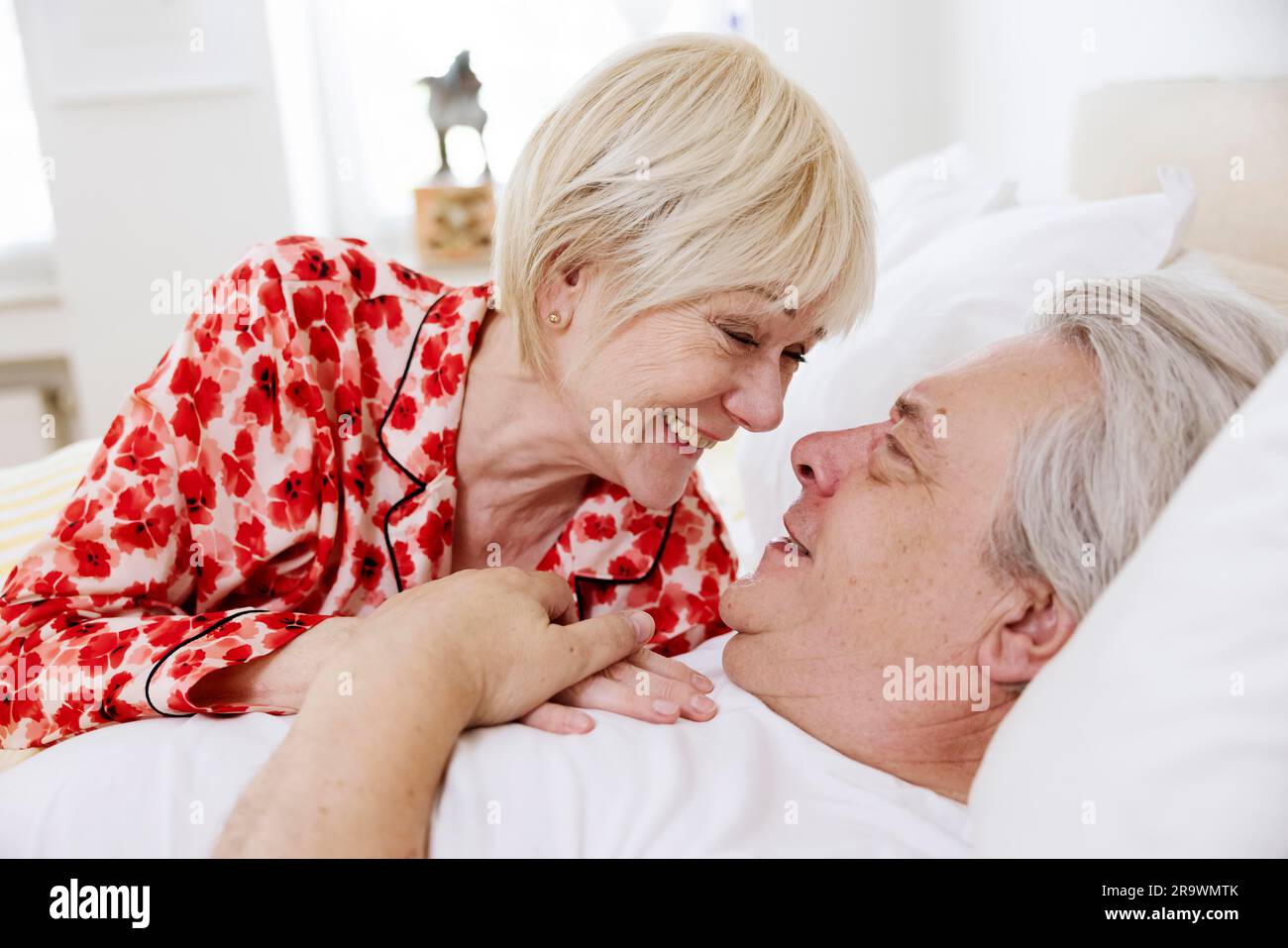 Couple âgé allongé ensemble dans un lit dans la chambre à coucher riant les uns les autres dans l'amour, Cologne, Rhénanie-du-Nord-Westphalie, Allemagne Banque D'Images