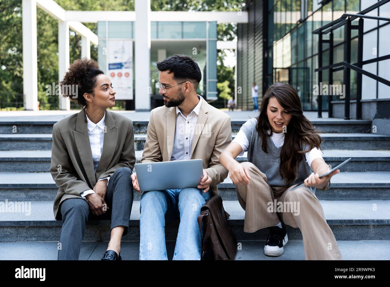 Réunions en extérieur pour les personnes en voyage d'affaires. Les hommes d'affaires et les femmes d'affaires en costume sont assis sur les marches de l'escalier. Pause de travail. Travail d'équipe Banque D'Images