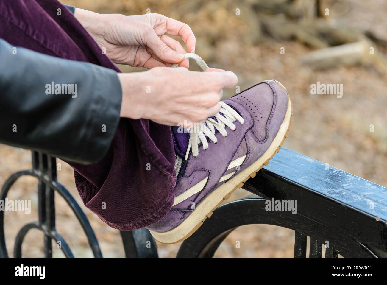 Une femme est de lier ses chaussures à lacets violet blanc, pendant une journée de randonnée en montagne Banque D'Images