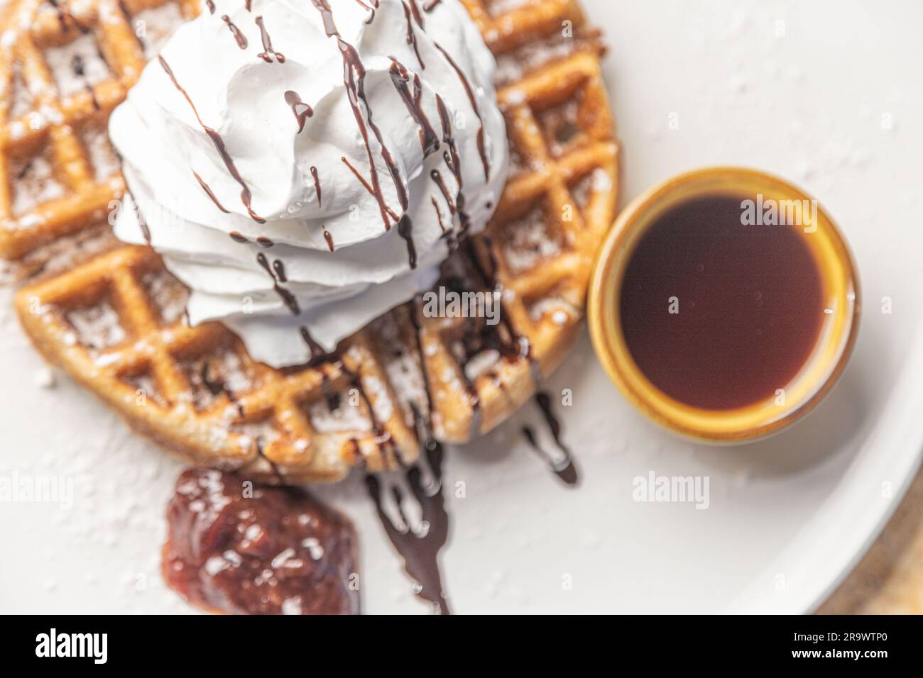 Une image en gros plan d'une délicieuse gaufre recouverte de crème fouettée crémeuse et de sirop de chocolat Banque D'Images
