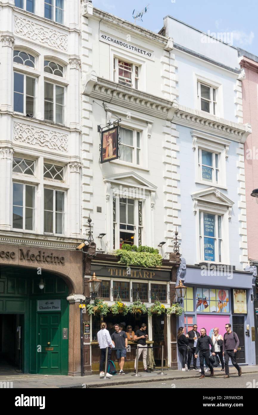Les gens buvant sur le trottoir devant le pub Harp à Chandos Street, Londres. Banque D'Images