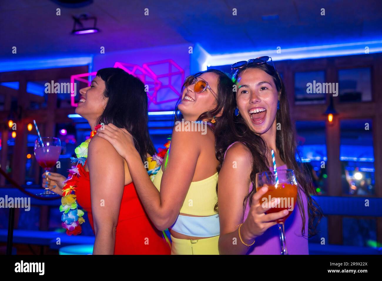 Des amies de boîte de nuit dansent avec des verres d'alcool souriant lors d'une soirée Banque D'Images