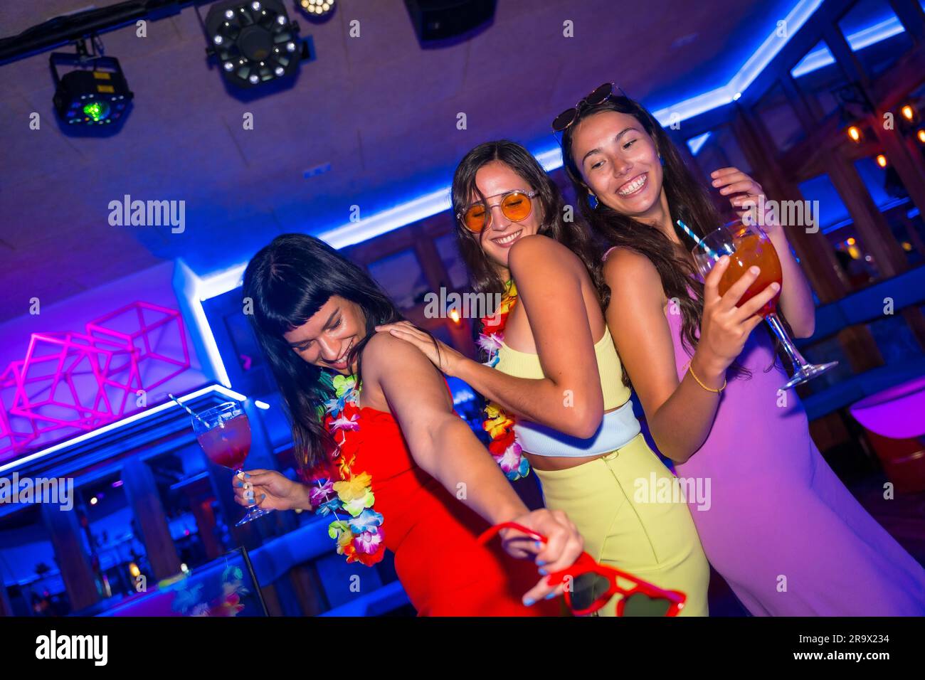 Des amies de boîte de nuit dansent avec des verres d'alcool souriant lors d'une soirée Banque D'Images