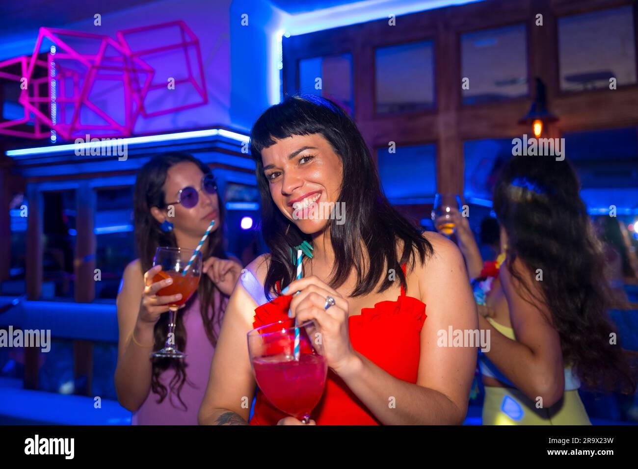Portrait belle femme avec un verre d'alcool dans une boîte de nuit lors d'une fête de nuit Banque D'Images