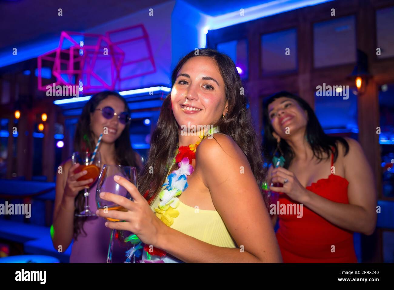 Portrait femme attrayante souriant avec un verre d'alcool dans une boîte de nuit lors d'une soirée Banque D'Images
