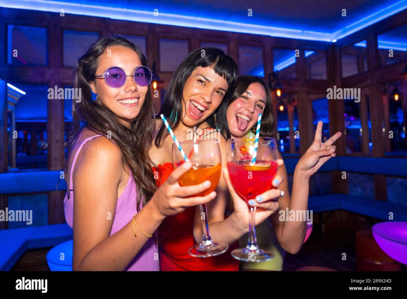 Portrait des femmes attirantes dans une boîte de nuit dansant avec les lunettes lors d'une soirée d'été dans un pub Banque D'Images