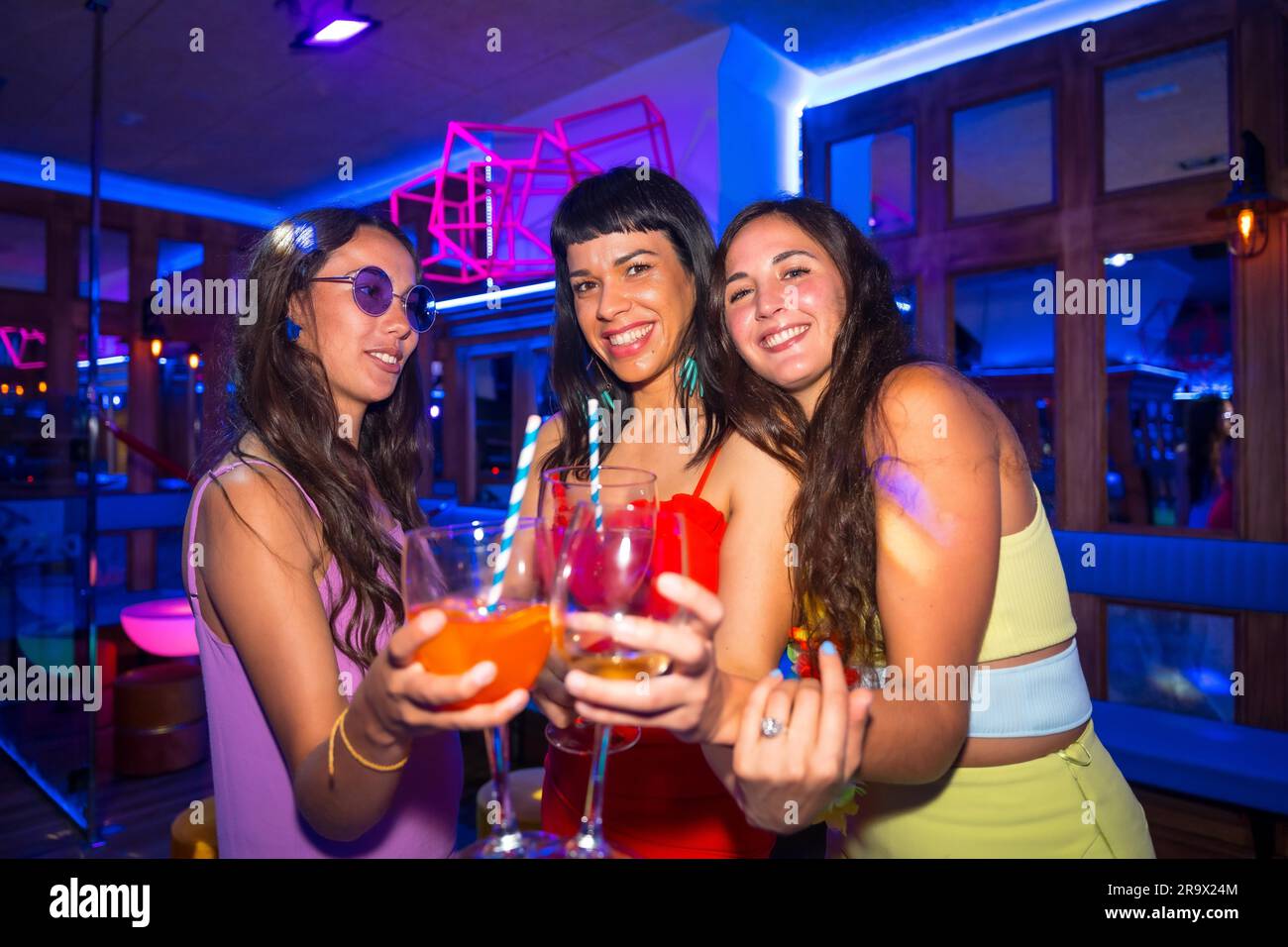 Portrait des femmes attirantes en toaster avec des verres à la discothèque lors de la soirée d'été au pub Banque D'Images