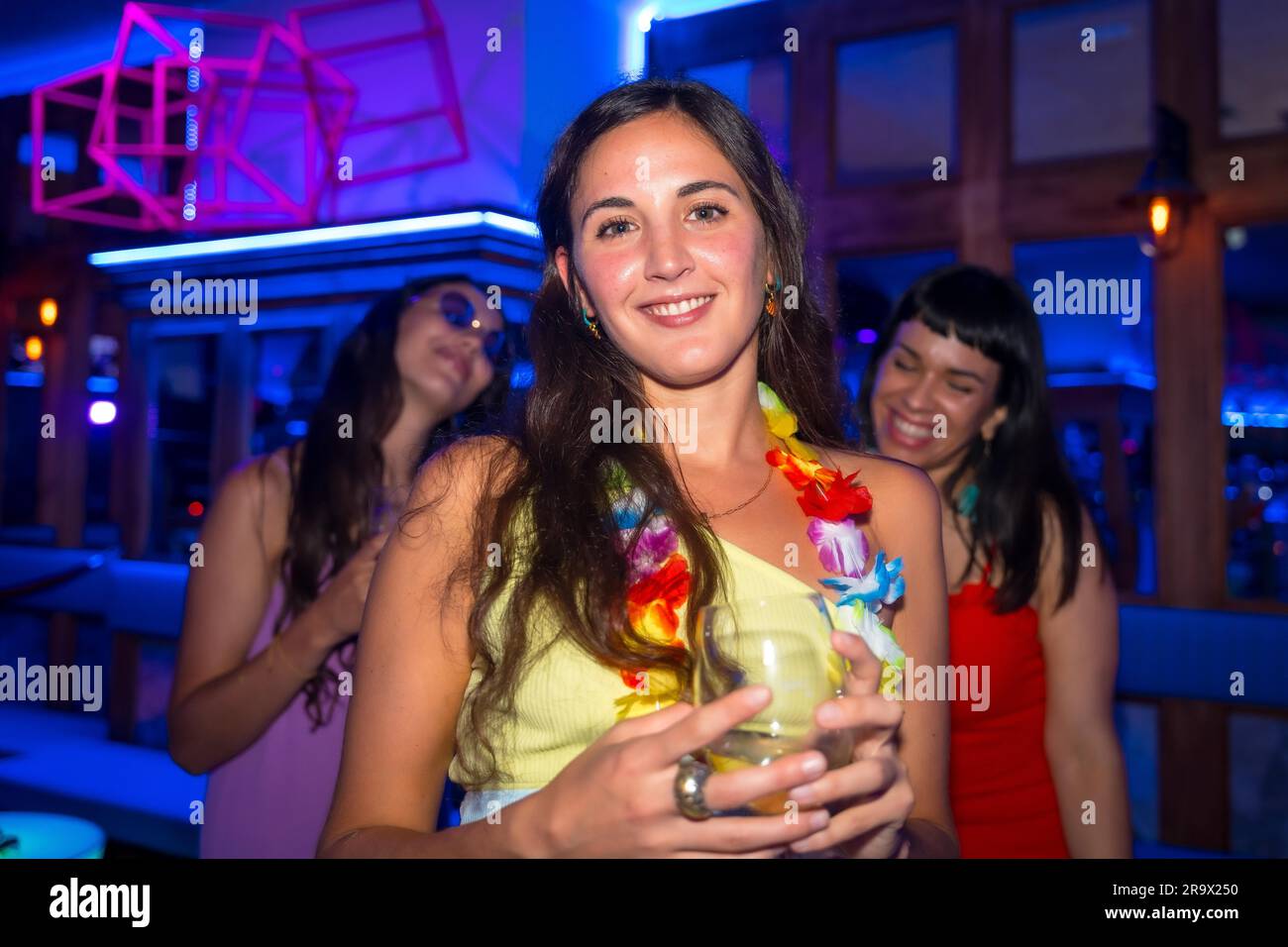Belle femme souriant avec un verre d'alcool dans une boîte de nuit lors d'une soirée Banque D'Images