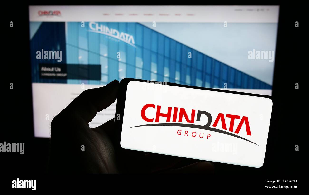 Personne tenant un téléphone portable avec le logo de la société chinoise de centre de données Chindata Group à l'écran en face de la page Web. Mise au point sur l'affichage du téléphone. Banque D'Images