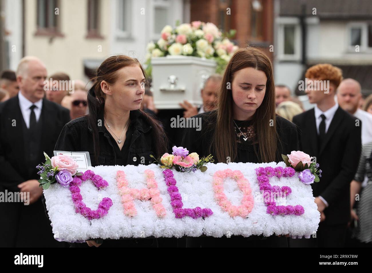 RETRANSMETTANT L'ORTHOGRAPHE RECTIFILANTE DES sœurs KIRSTIE Chloe Mitchell Kirstie (à gauche) et Nadine portent une couronne devant son cercueil, le long de la rue Larne, à Ballymena. Date de la photo: Jeudi 29 juin 2023. Banque D'Images